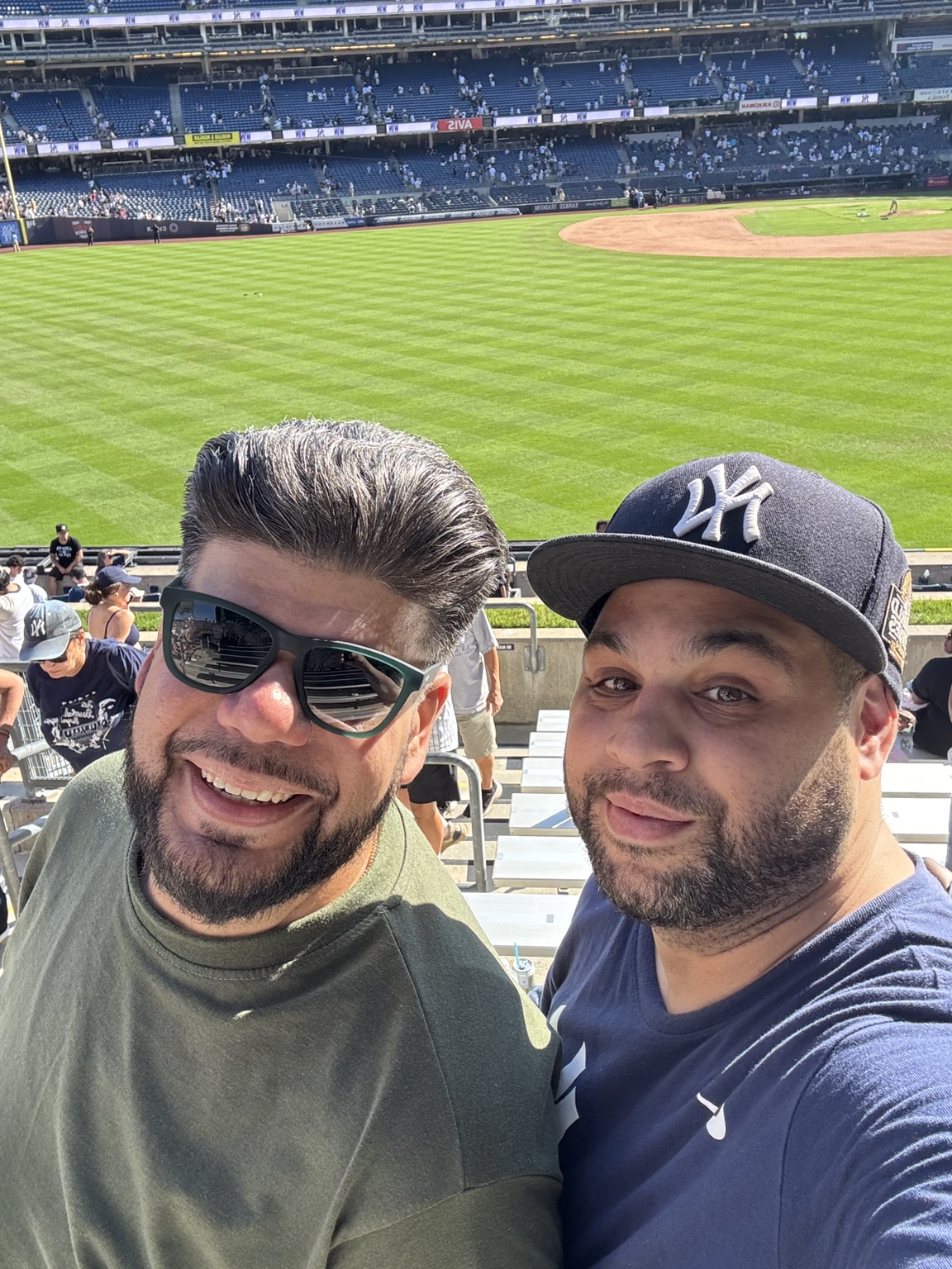 John and his friend Dave smiling together in the stands at a baseball game
